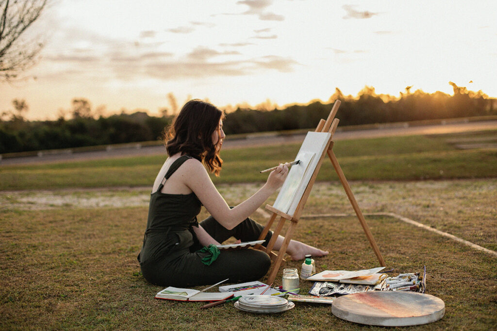 Woman sitting outside painting on a canvas