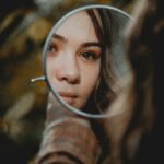 woman looking in the mirror while sitting outside